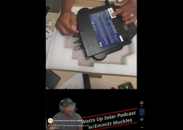Hands unboxing a black power inverter with a blue label, placed in foam packing material in a box.