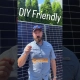 Man in a blue shirt stands in front of solar panels, with overlay text 'DIY Friendly' and 'AND I DO MEAN YOU CAN HOOK UP'—emphasizing DIY solar hookup.